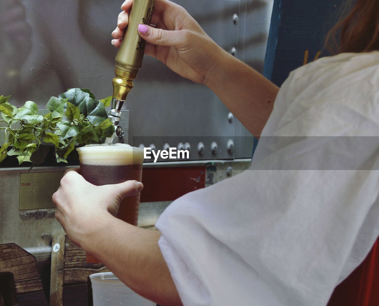 Cropped image of woman hand filling glass from beer tap