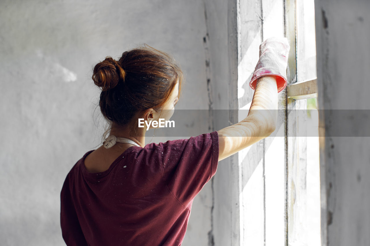 Rear view of woman standing against wall