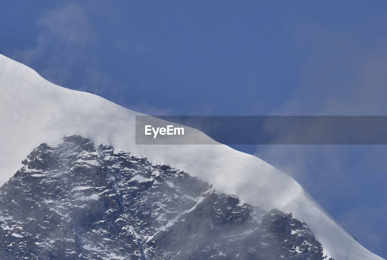 Low angle view of snowcapped mountain  ridge against sky
