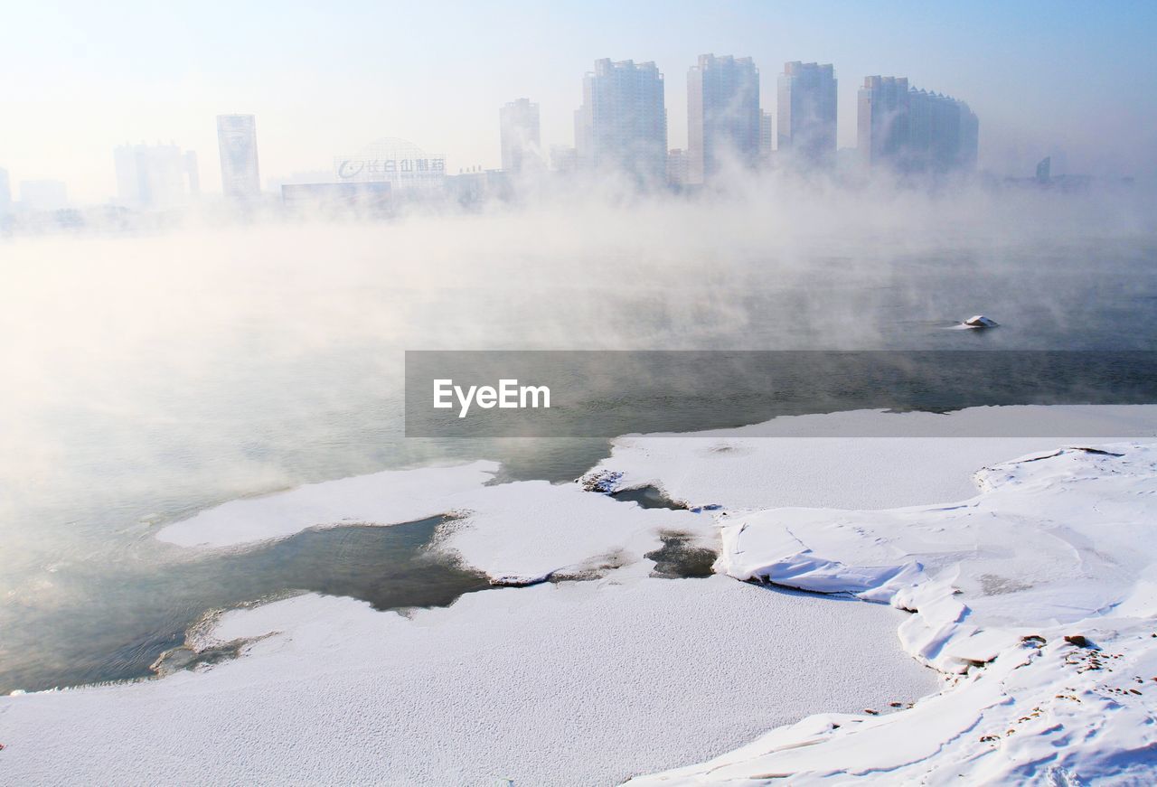 Aerial view of city by sea against sky during winter