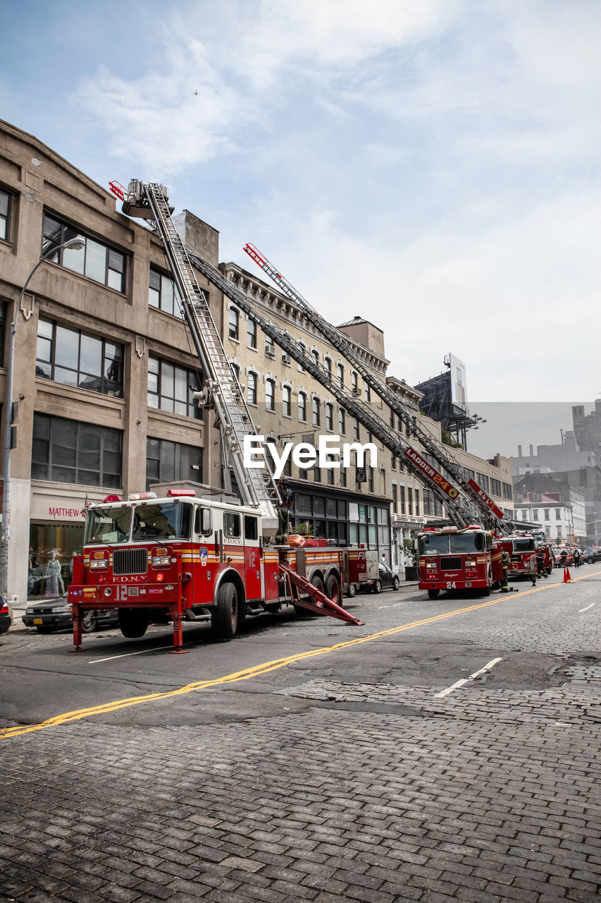 Fire engines by buildings in city against sky