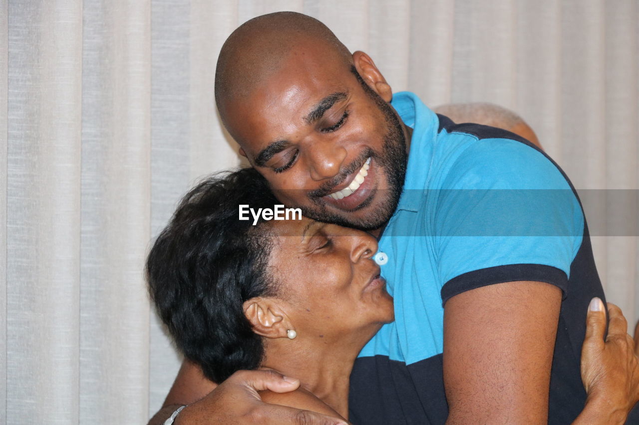 Close-up of mother and son embracing at home