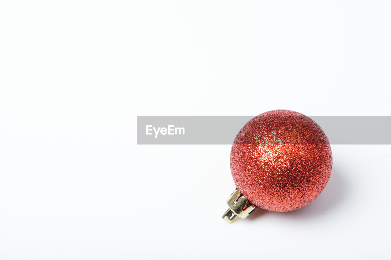 Close-up of red bauble over white background