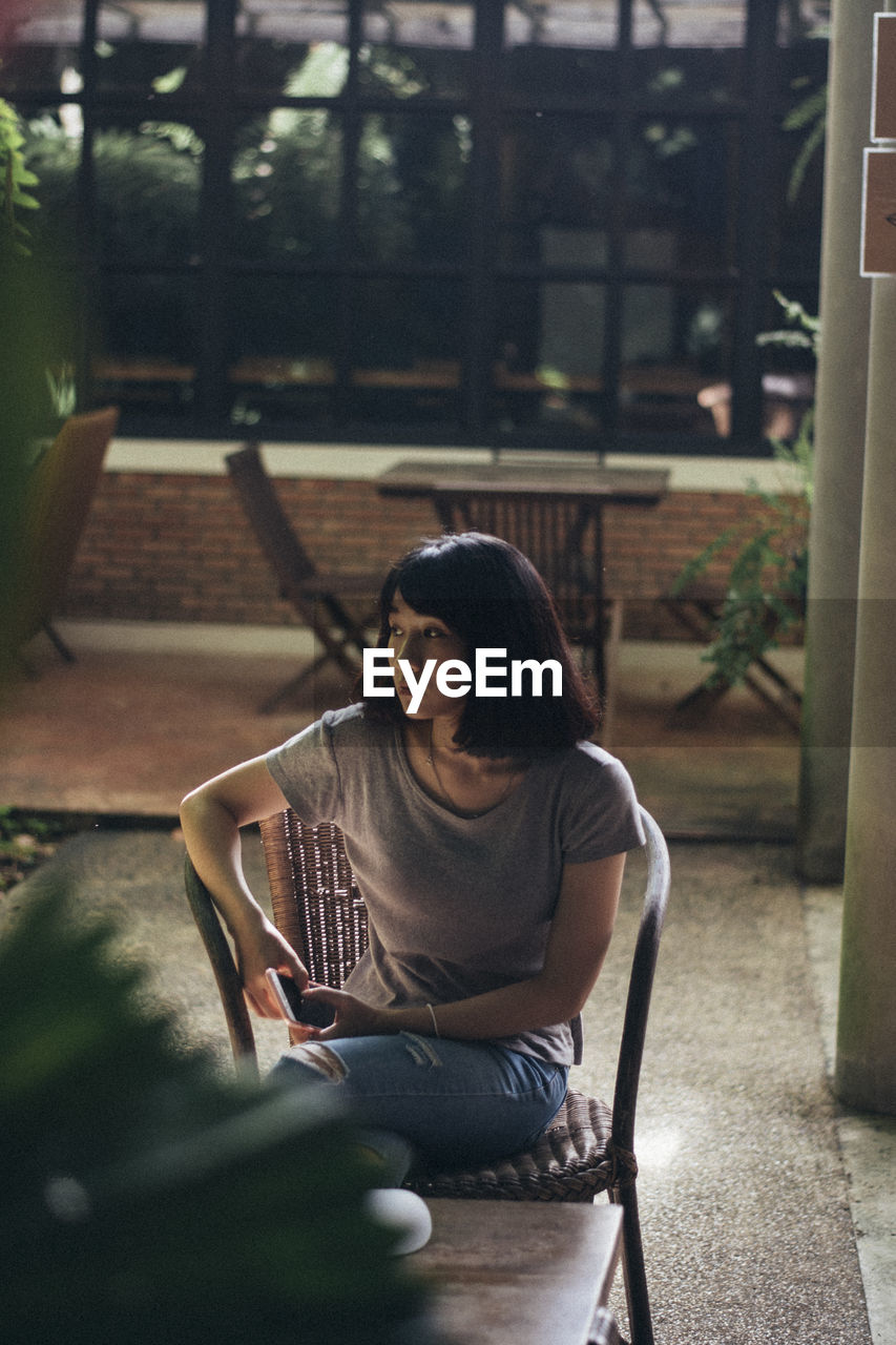 Thoughtful woman sitting on chair in restaurant 