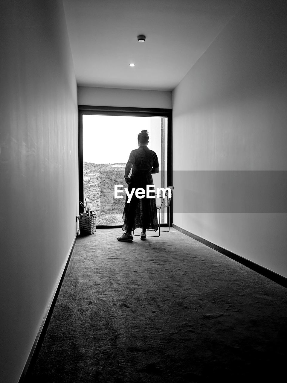 REAR VIEW OF MAN WALKING IN BUILDING CORRIDOR