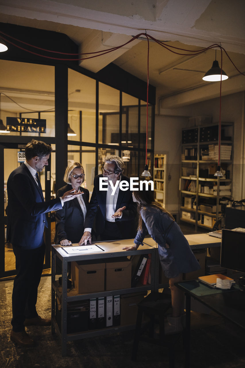 Business people discussing with girl and shining tablet in office