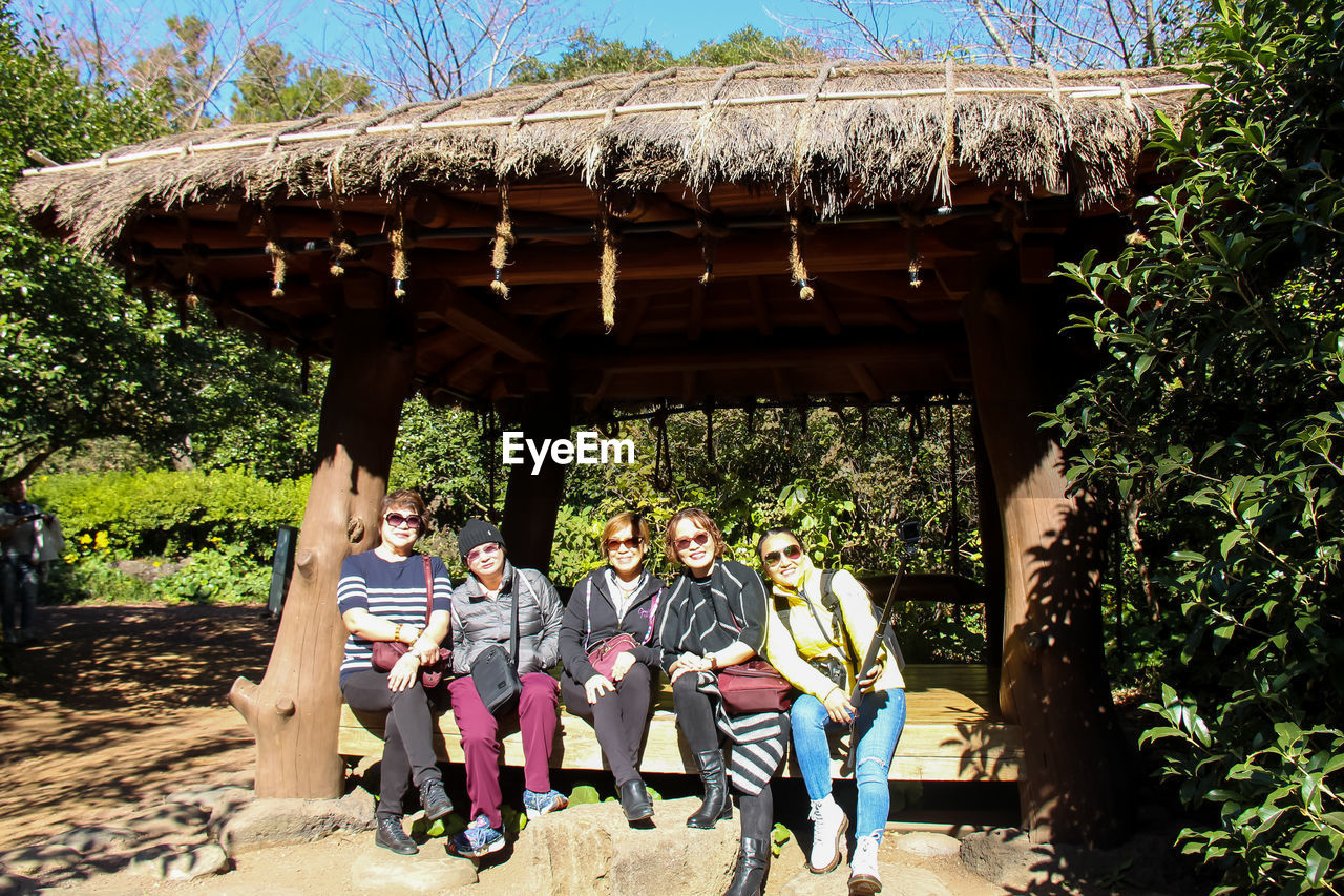 GROUP OF PEOPLE SITTING ON TREE TRUNK