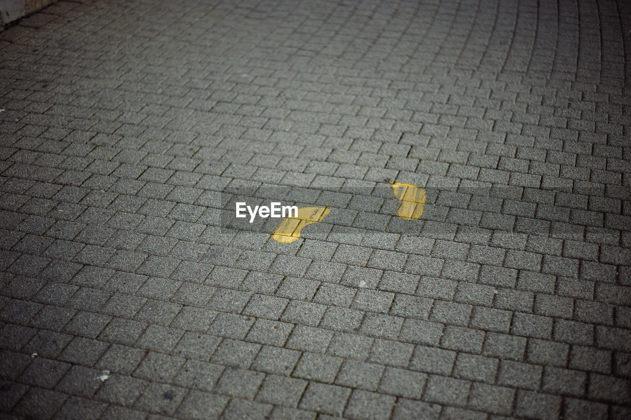 High angle view of yellow arrow symbol on footpath