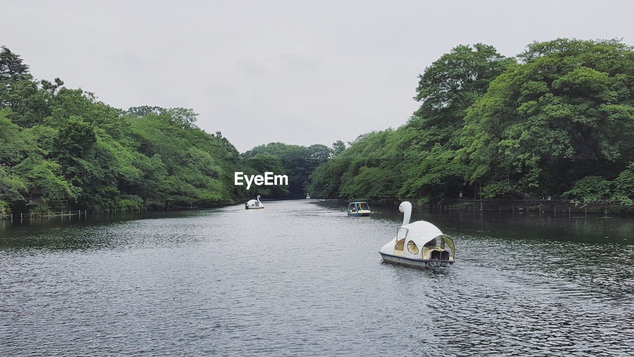 Paddleboats sailing in river against sky