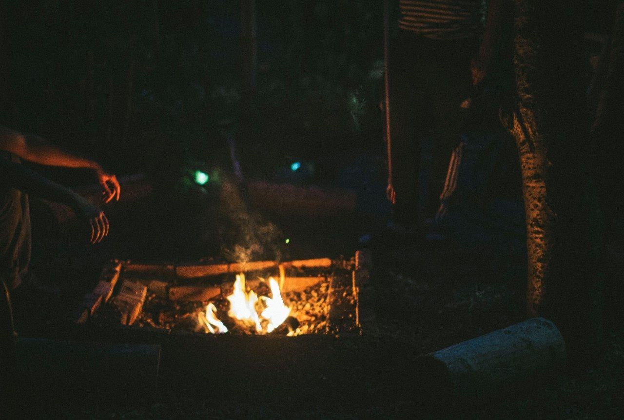 People enjoying warmth of bonfire at night