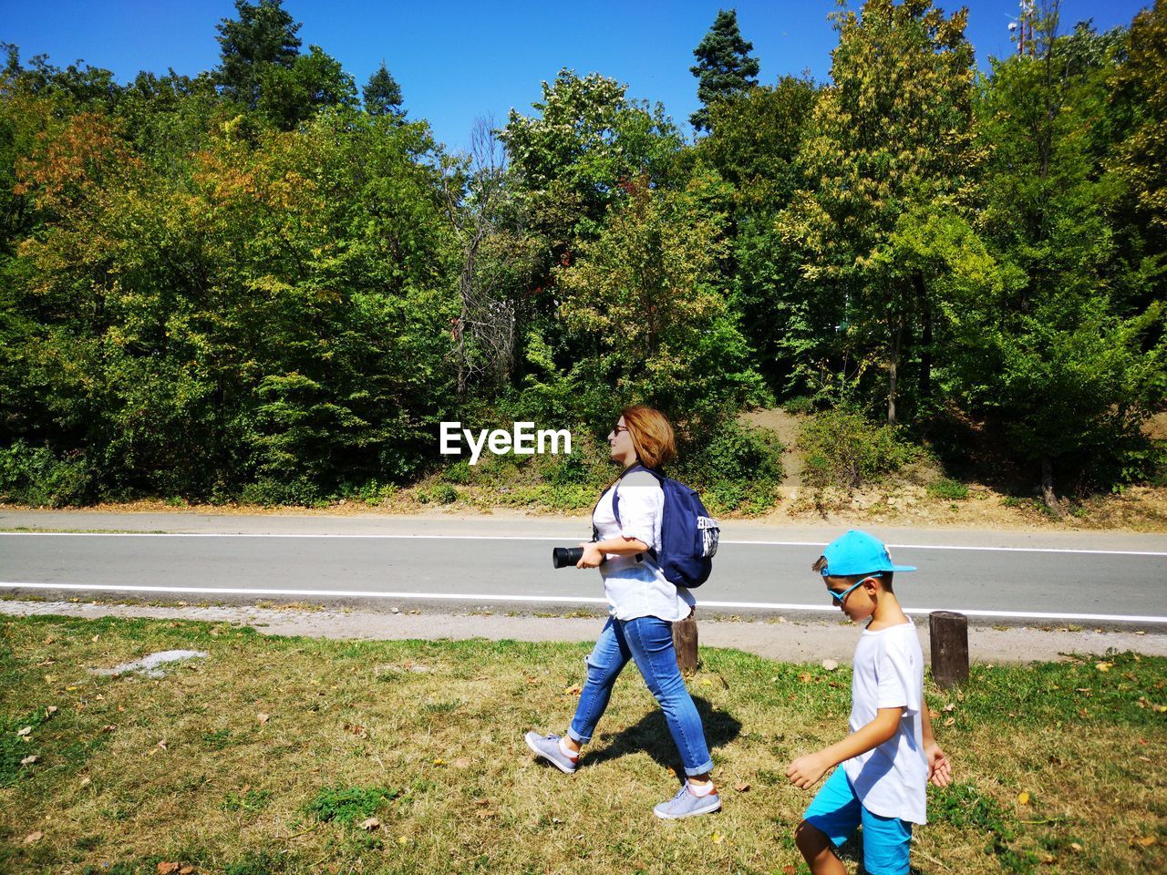 Side view of boy with mother walking on grassy field