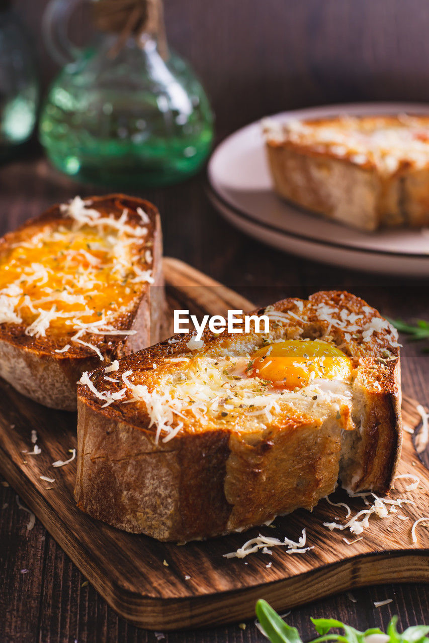 Bread baked with egg and cheese on a cutting board vertical view