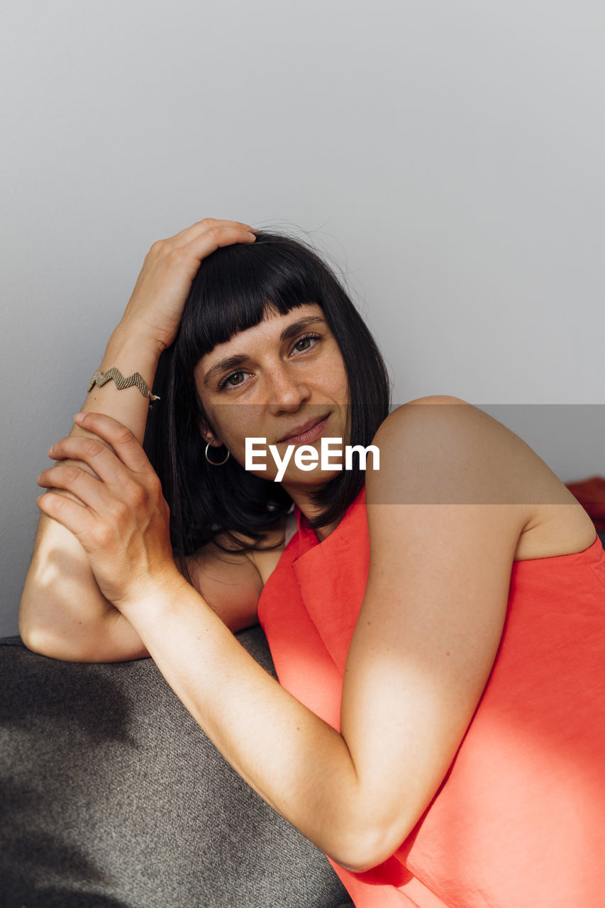 Smiling woman sitting on couch at home