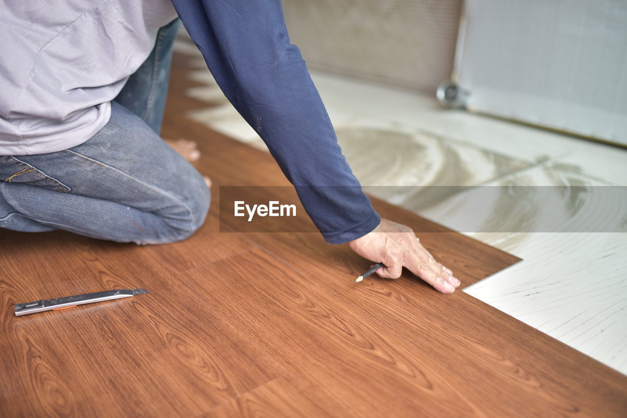 Midsection of man working on wooden floor