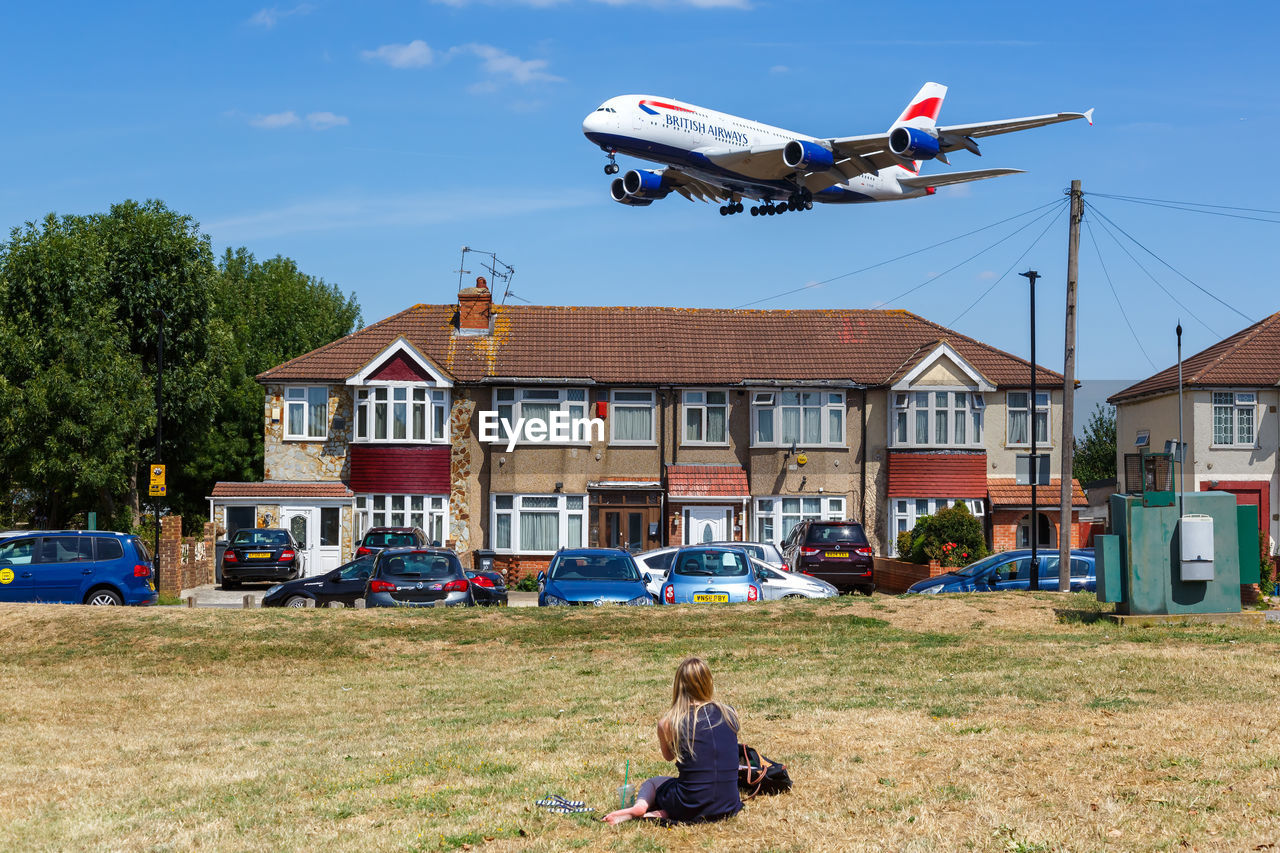 WOMAN FLYING BY BUILDING