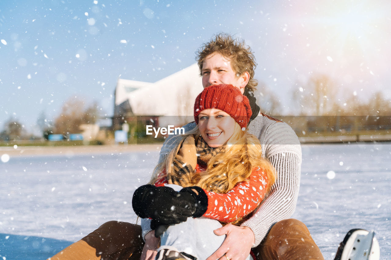 Portrait of smiling young woman with man on sledge