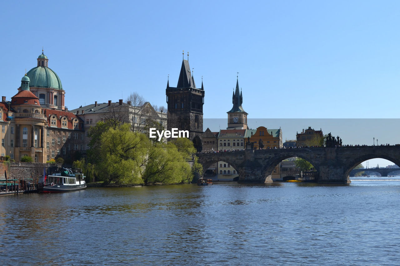 Bridge over river in city against clear sky