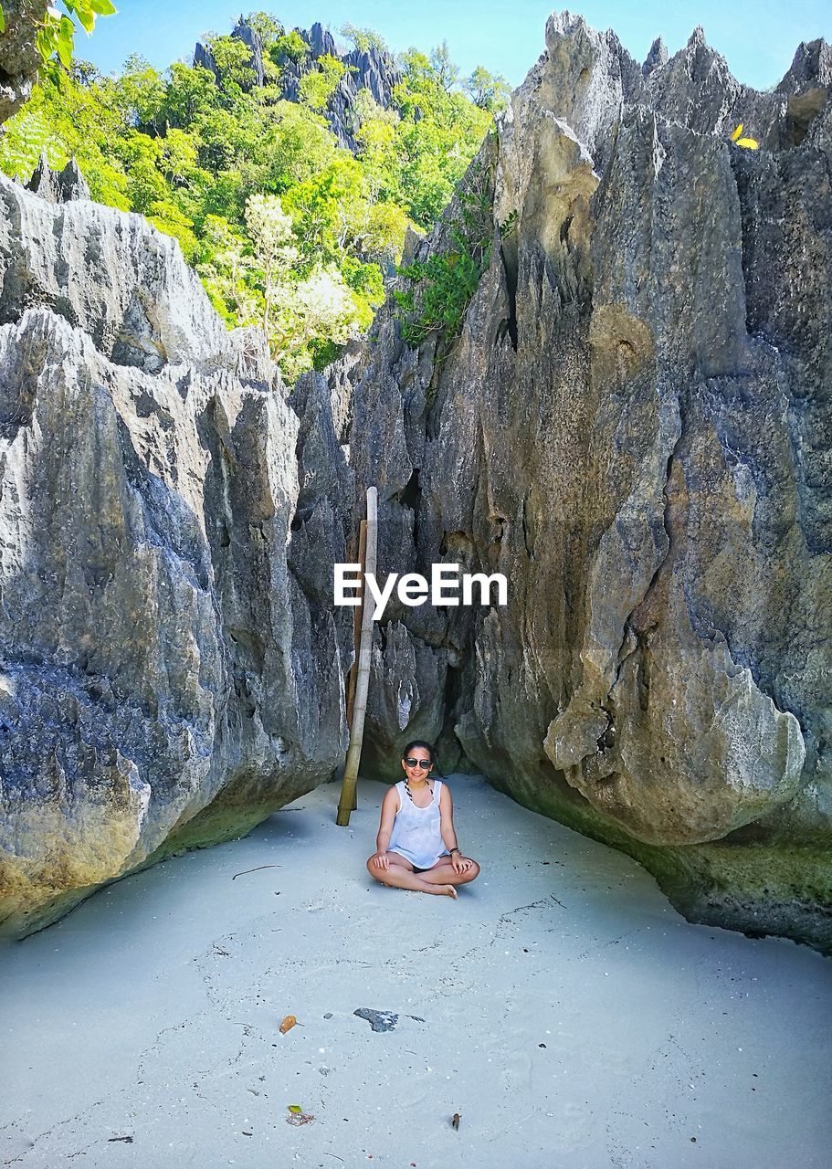 Woman sitting against rock formations at beach