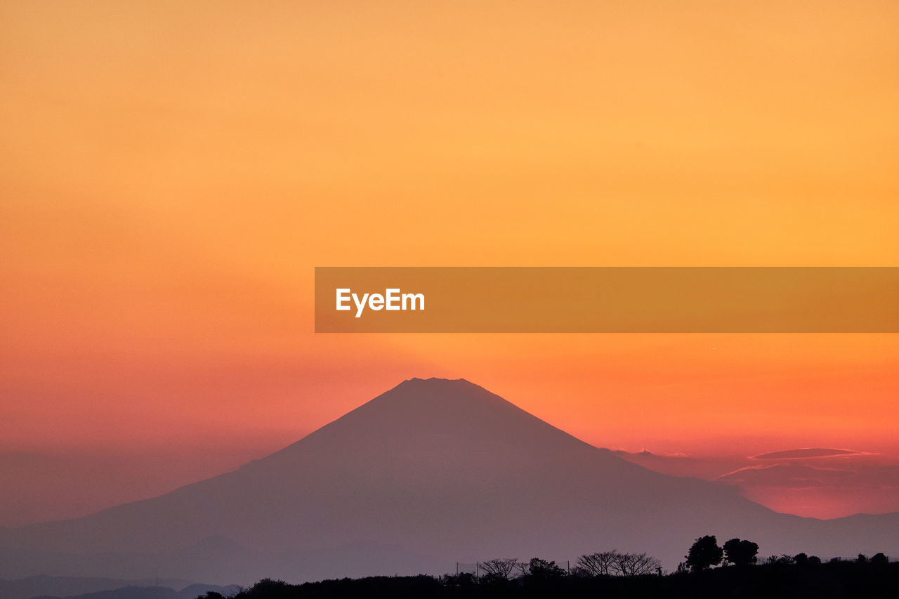 Scenic view of silhouette volcano mountain against orange sky