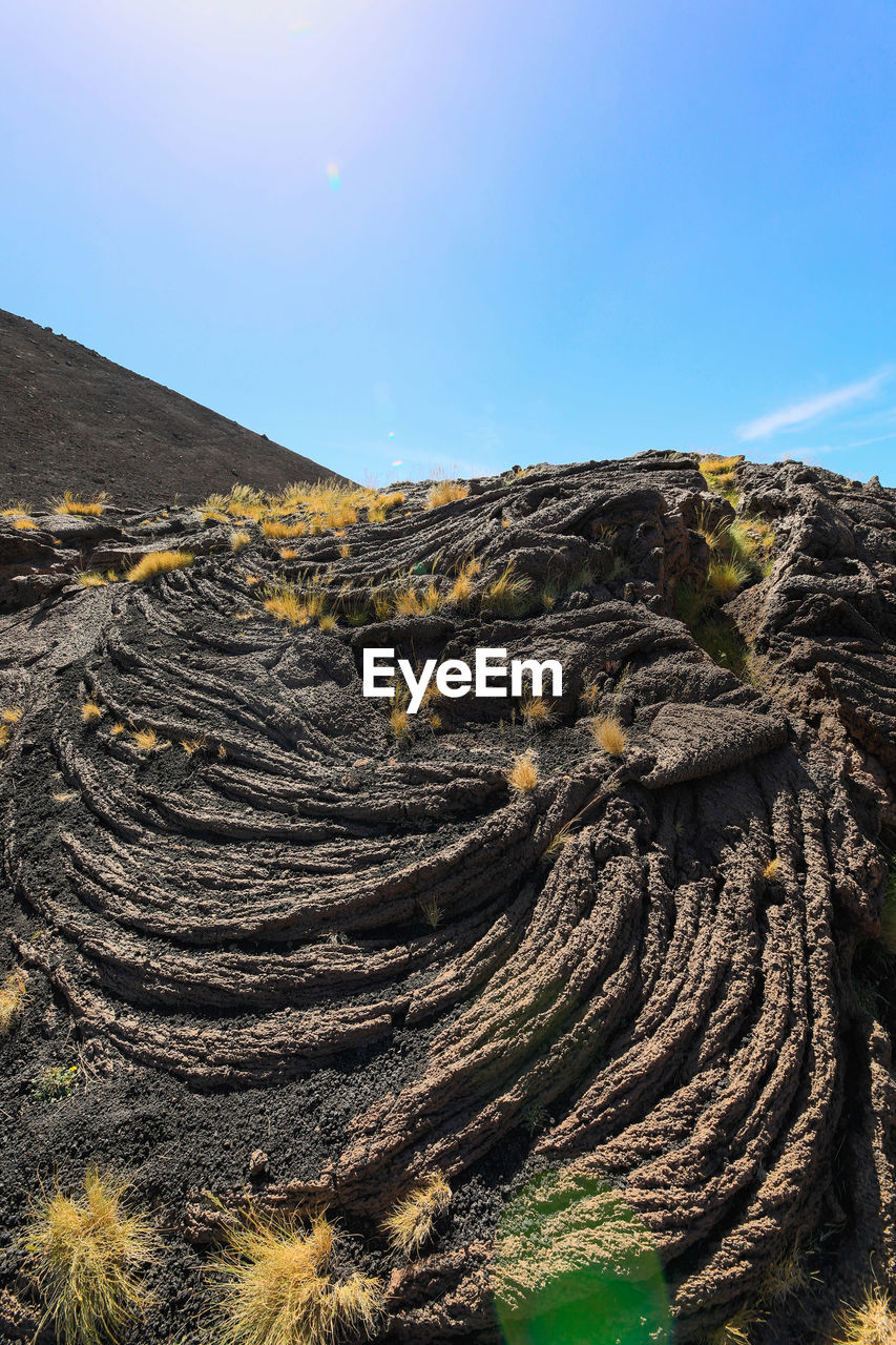 landscape, sky, environment, mountain, rock, nature, scenics - nature, land, terrain, beauty in nature, cliff, non-urban scene, no people, geology, wilderness, tranquility, travel destinations, sea, sunlight, outdoors, volcano, day, rock formation, plateau, travel, mountain range, clear sky, tranquil scene, physical geography, blue, coast, plant, sunny, natural environment, soil, volcanic landscape, extreme terrain, desert, tourism