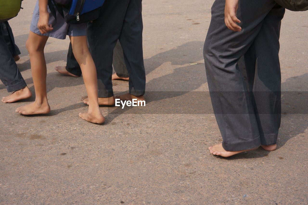 Low section of people with bare feet walking on road