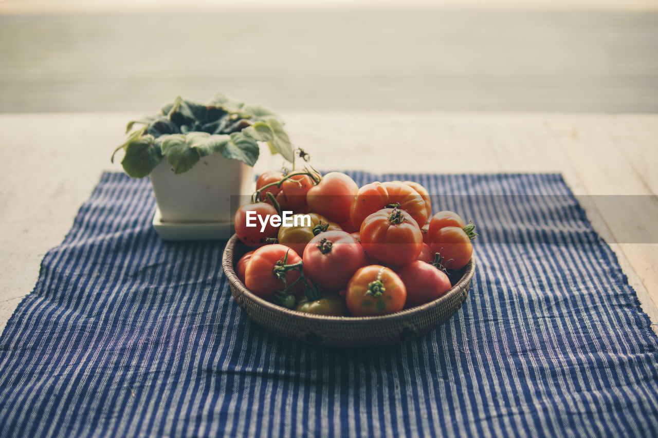 Fresh raw red tomatoes in basket on table