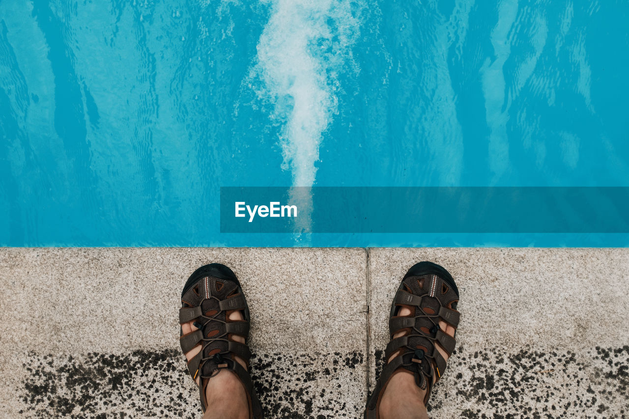 Low section of man standing by swimming pool