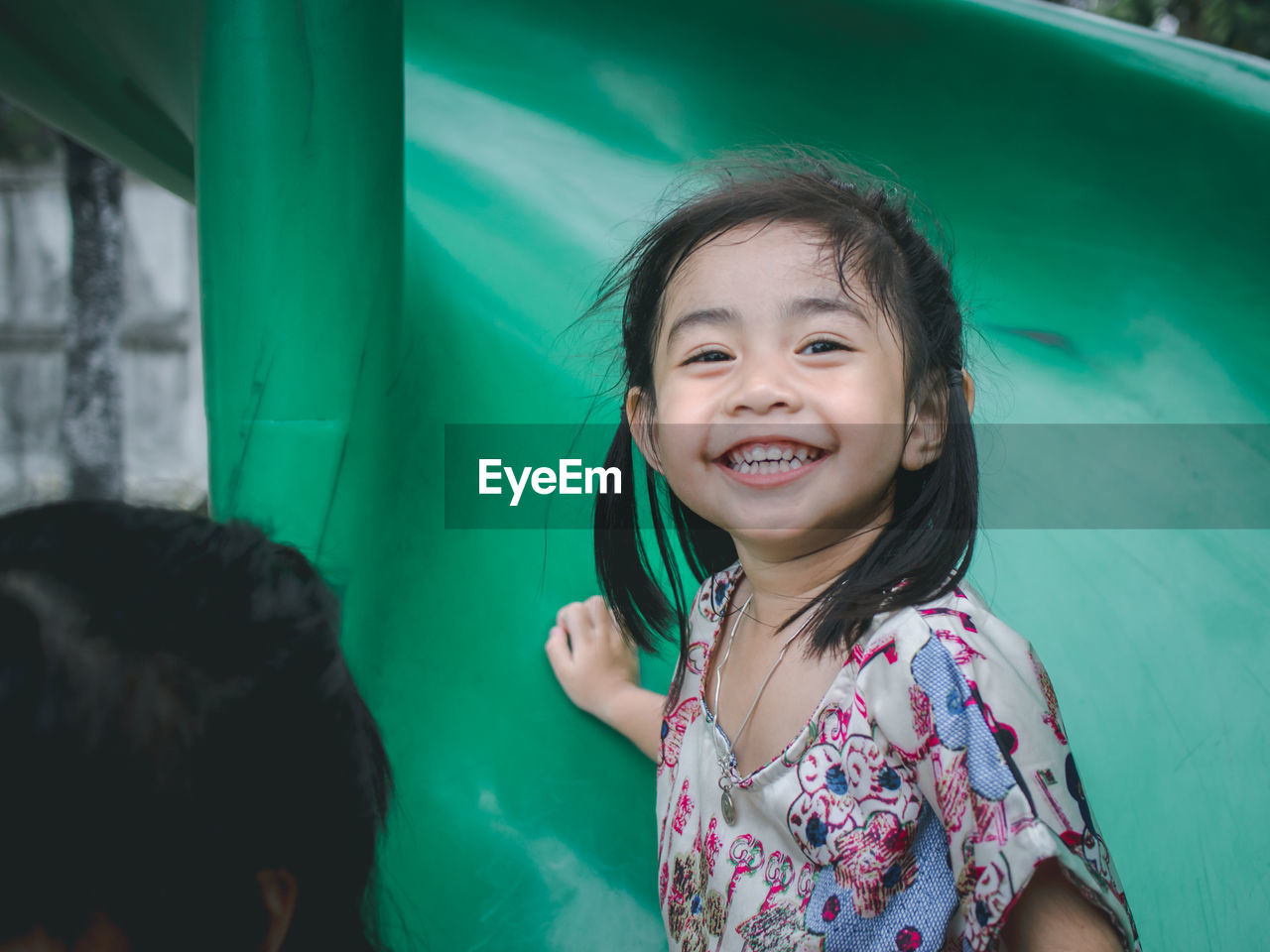 Portrait of cute smiling girl sliding in playground