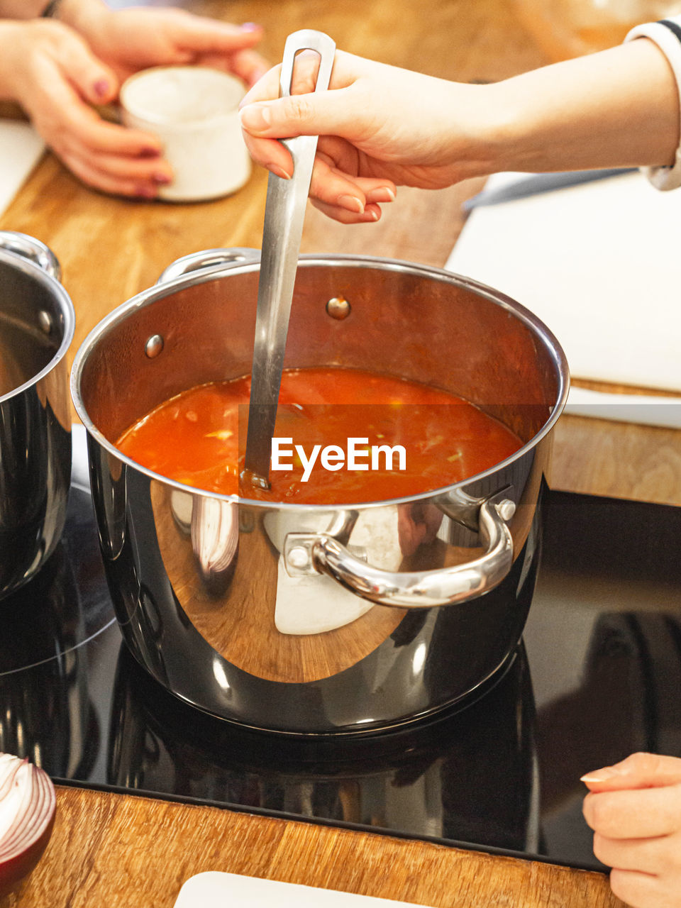 Uncertain woman preparing soup in  kitchen at home. women stirs tomato soup in  saucepan on  stove.