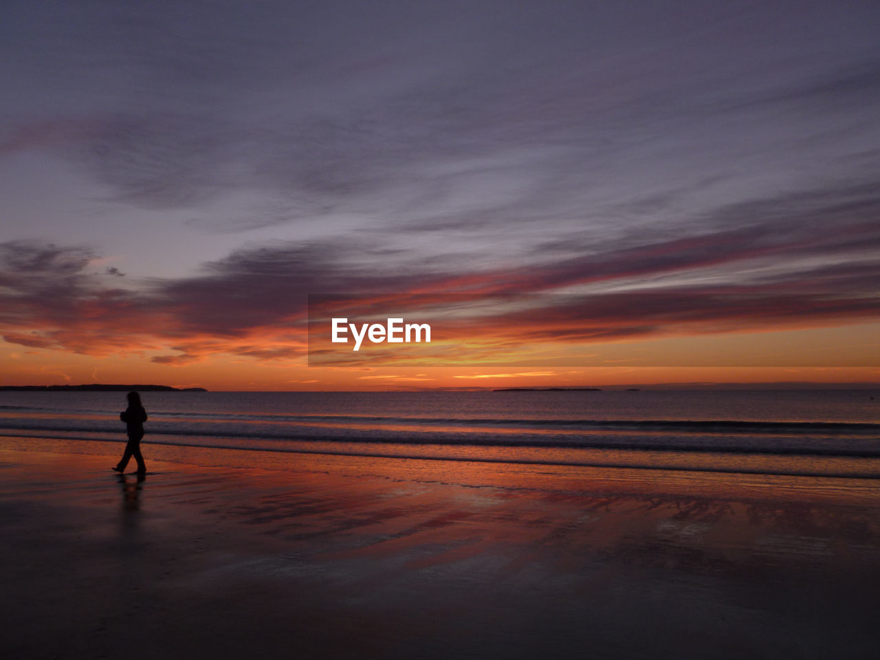 Silhouette woman walking at beach against sky during sunset
