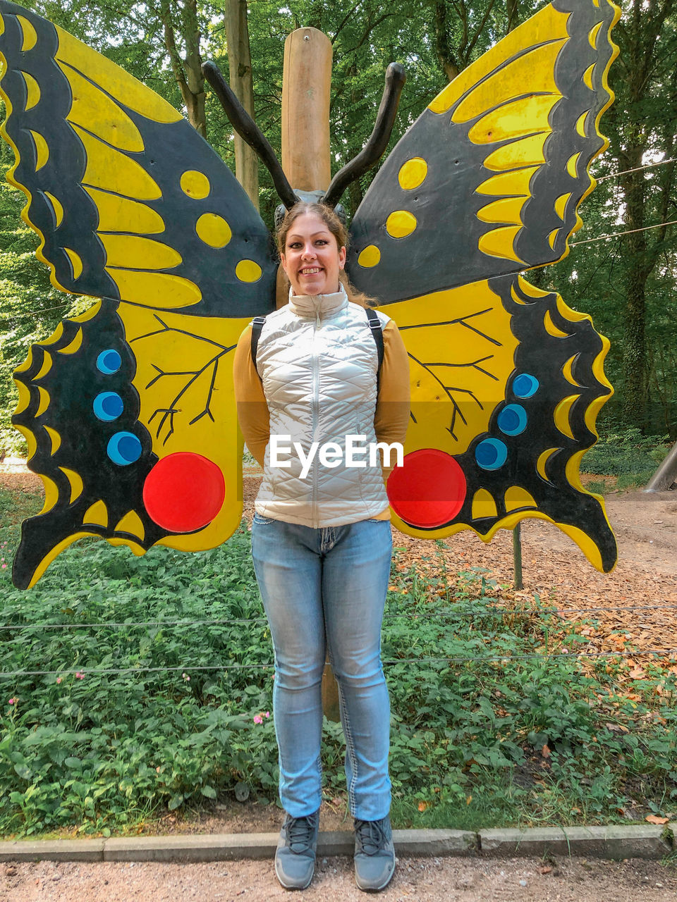 butterfly, one person, full length, yellow, front view, standing, art, moths and butterflies, casual clothing, smiling, portrait, adult, leisure activity, creativity, day, young adult, looking at camera, happiness, lifestyles, plant, painting, multi colored, mural, flower, women, outdoors, emotion, nature, person, tree, leaf, clothing, representation, autumn, animal representation, fun, graffiti, insect