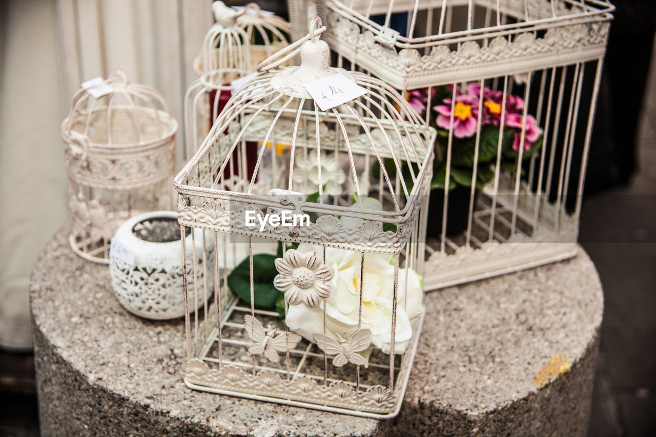 High angle view of flowers in white birdcage on stone
