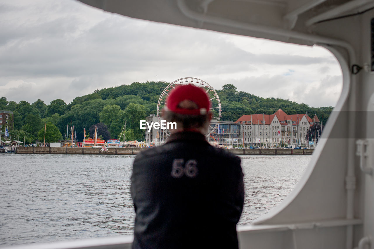 REAR VIEW OF MAN LOOKING AT VIEW OF RIVER