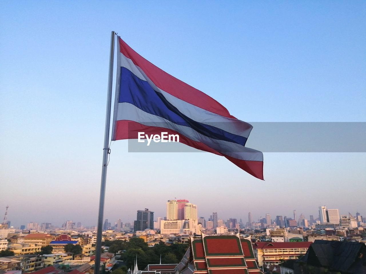 Flag against buildings in city against clear blue sky