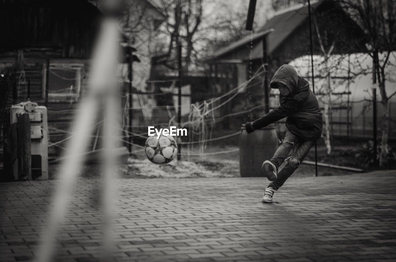 Full length of boy playing soccer ball