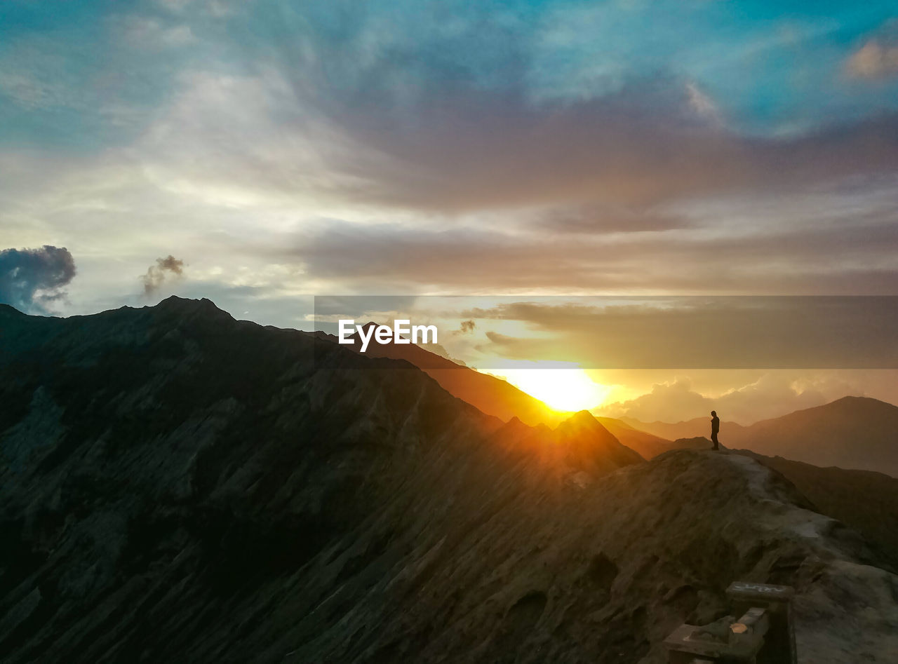 Man standing on mountain against sky during sunset