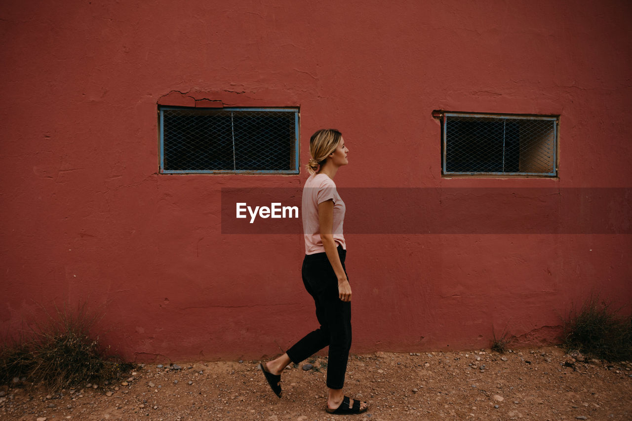 Side view of young woman walking by building