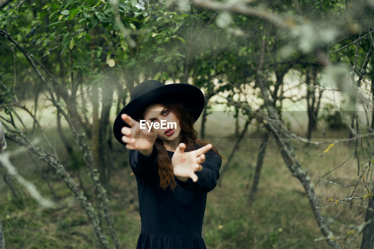 portrait of young woman standing against trees