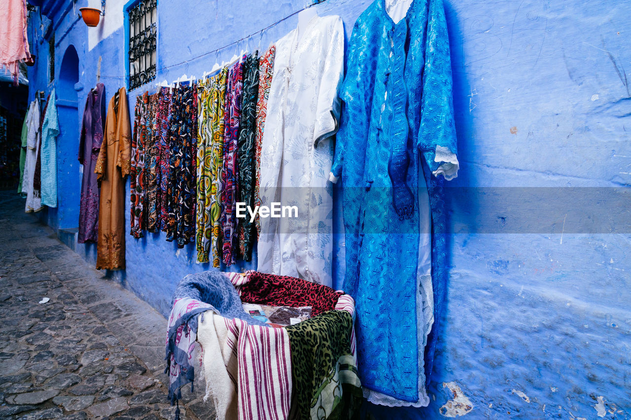 Abayas and scarfs for sale on blue wall, chefchaouen, morocco.