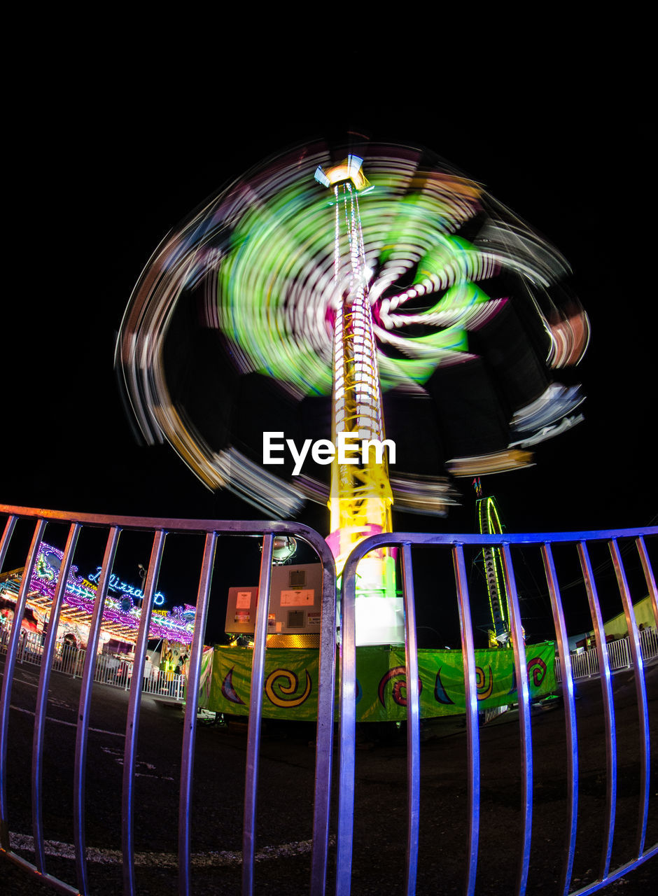 Low angle view of illuminated ride against clear sky at night