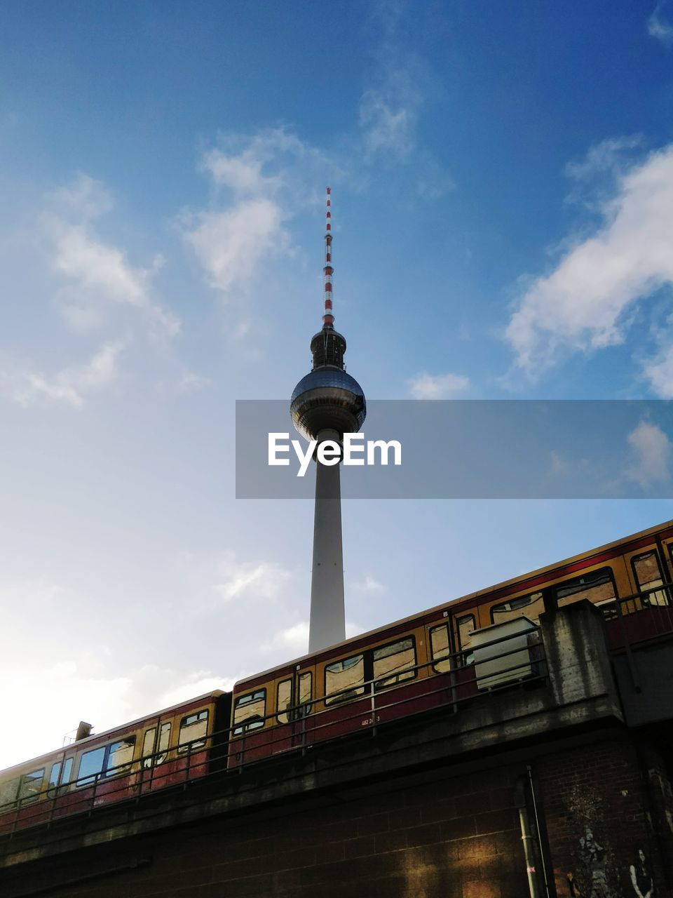 Low angle view of berlin tv communications tower and train against sky