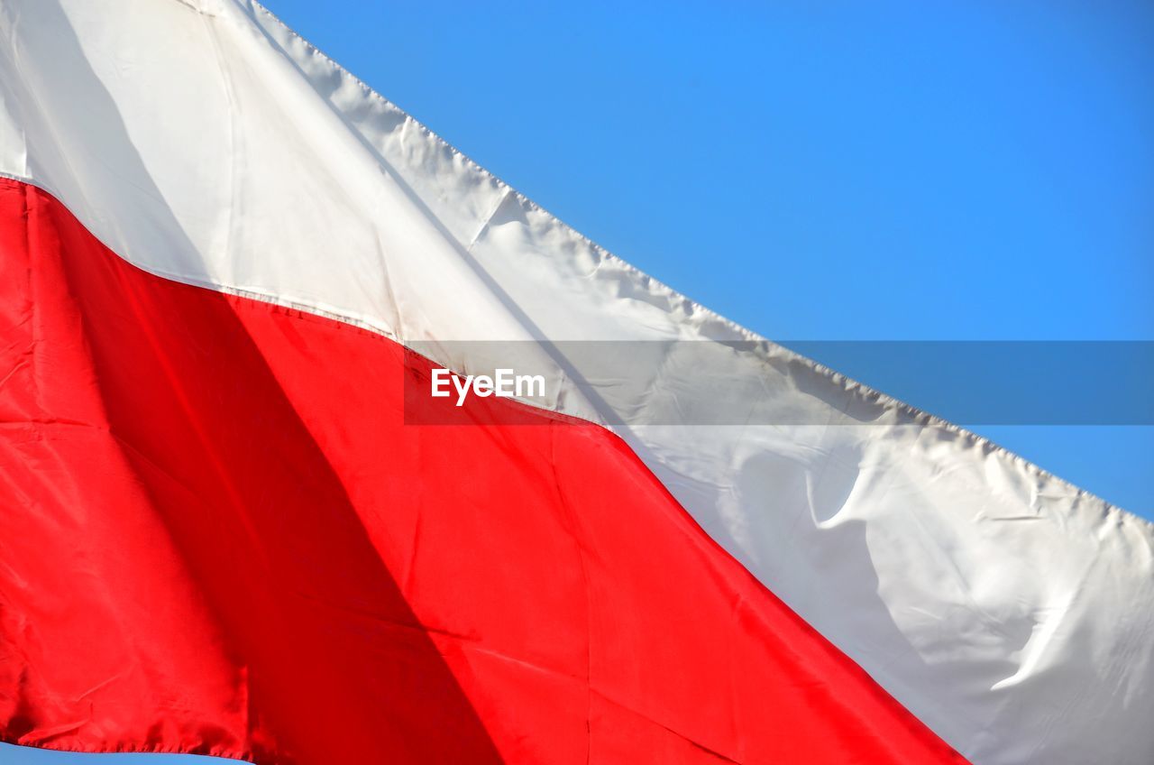 LOW ANGLE VIEW OF FLAGS AGAINST BLUE SKY