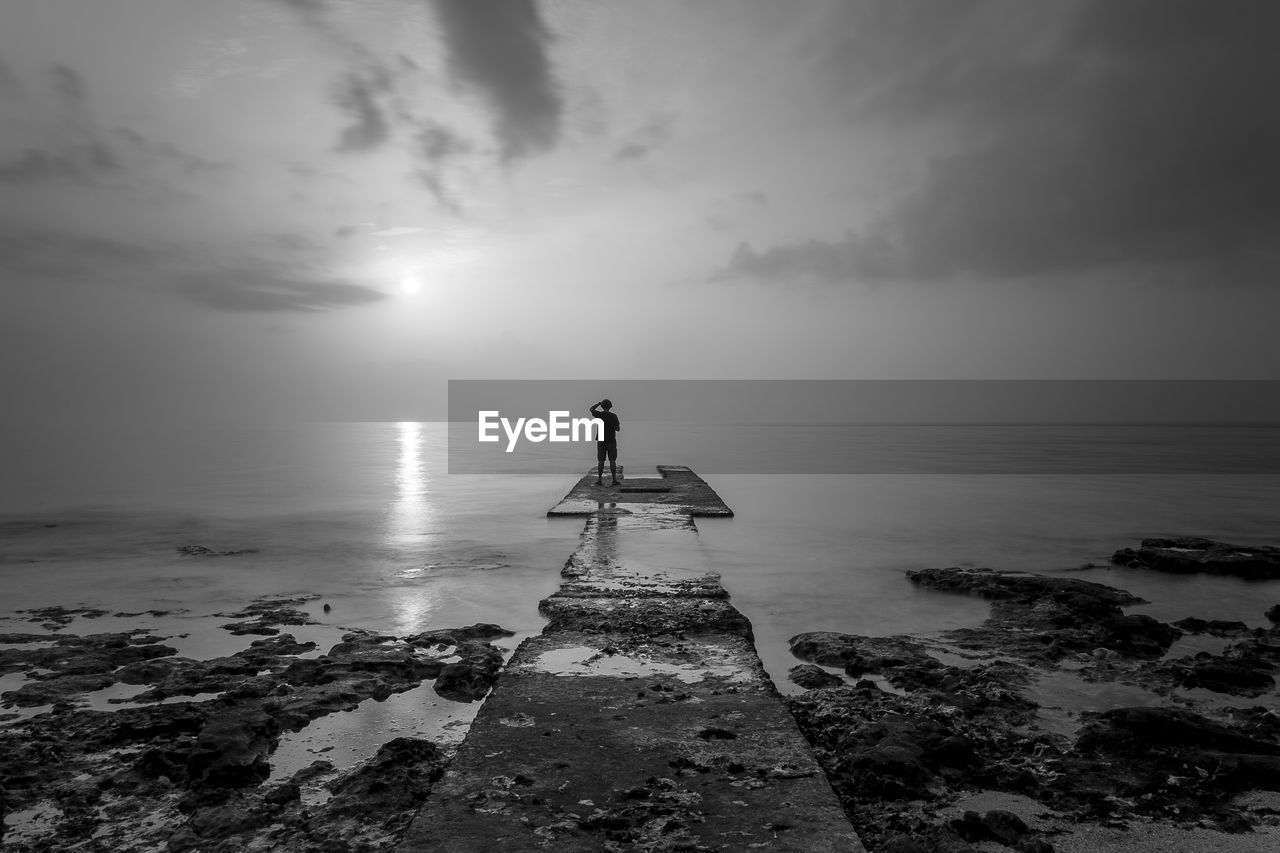 Man standing in sea against sky