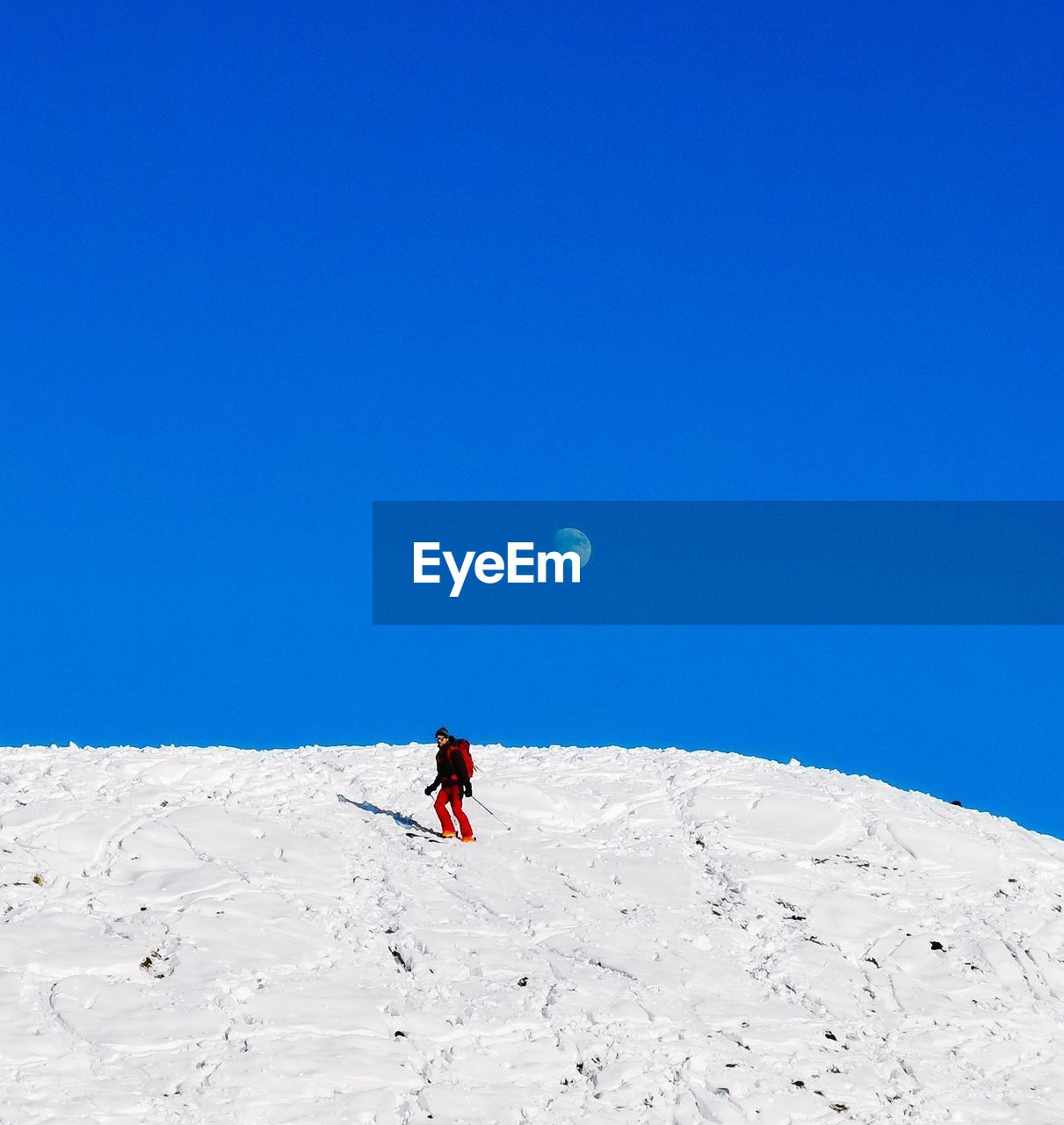 Full length of person on snowcapped mountain against clear blue sky