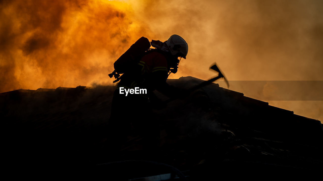 Side view of silhouette firefighter during sunset