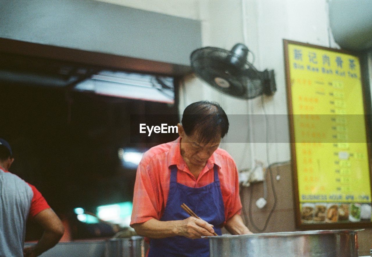 REAR VIEW OF MAN WORKING IN RESTAURANT