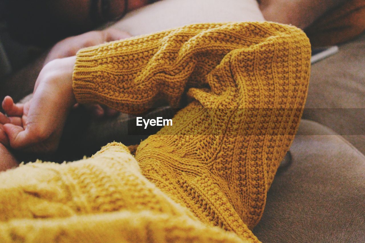 Close-up of person wearing sweater lying on sofa