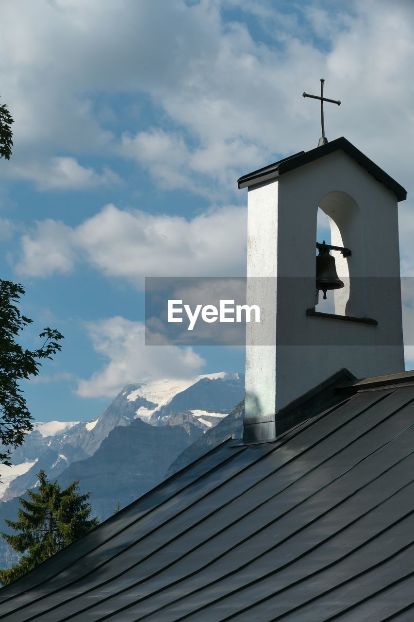 Low angle view of cross on roof of building against sky