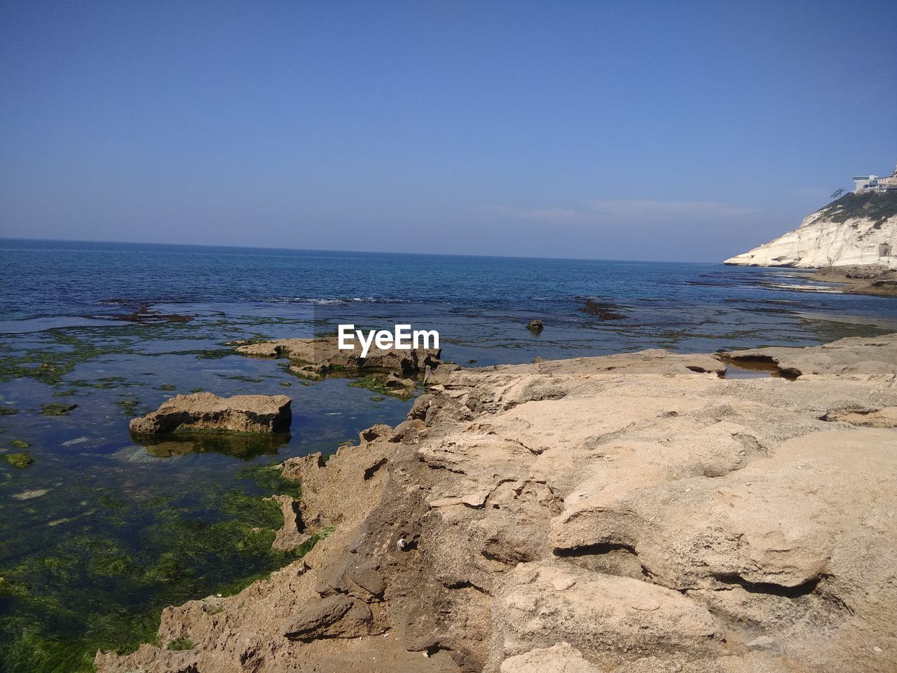 ROCKS ON BEACH AGAINST CLEAR SKY