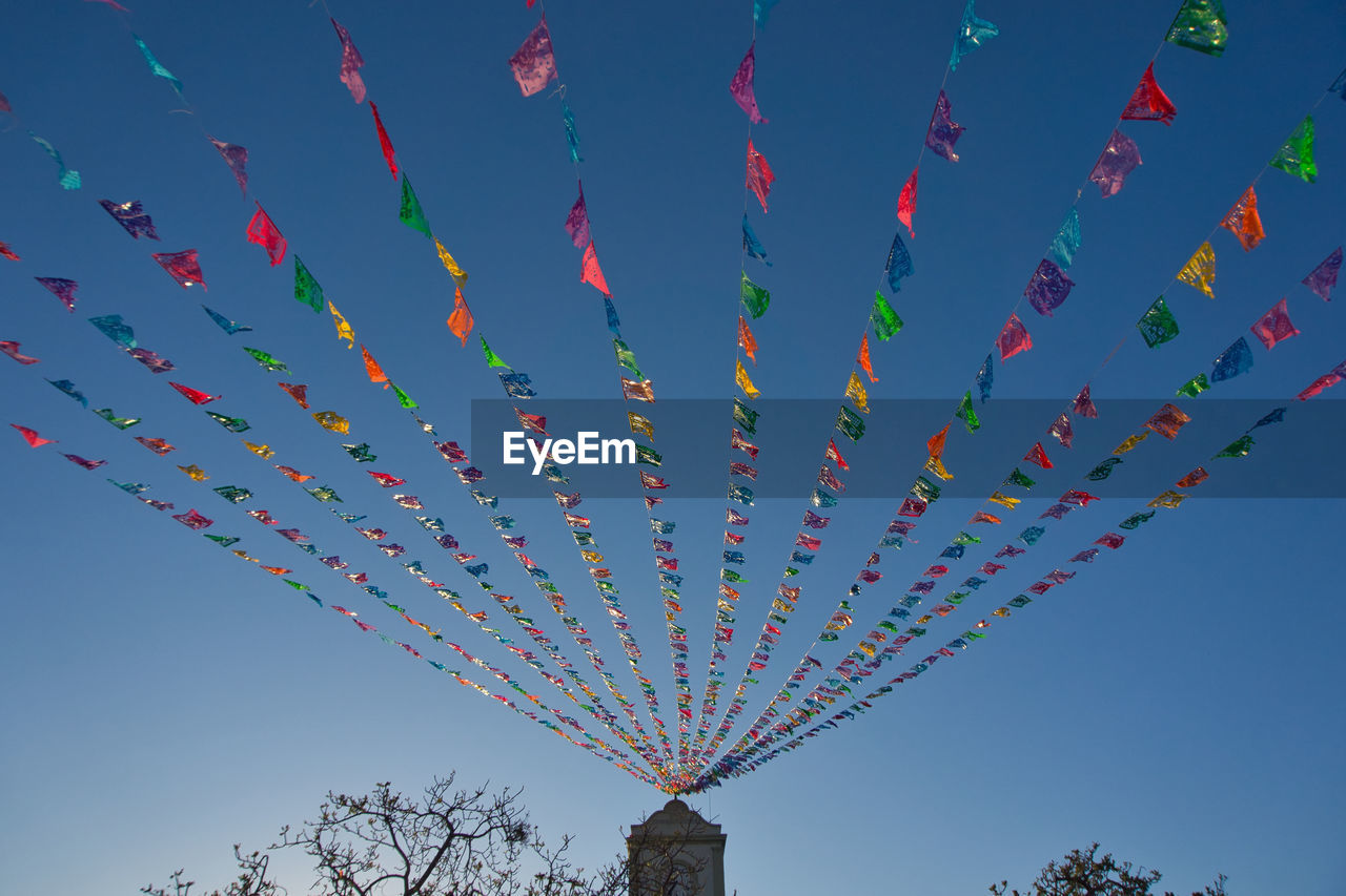 sky, celebration, nature, multi colored, blue, low angle view, toy, clear sky, no people, event, tradition, flying, flower, decoration, tree, outdoors, plant, day, architecture, large group of objects